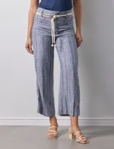 Pantalón de lino a rayas verticales azules y blancas, con corte ancho, pretina con pasadores, cierre y botones. Incluye cinto de soga con nudo.