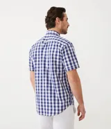 Camisa de manga corta con estampado de cuadros azules y blancos. Fabricada con una mezcla de algodón y poliéster, la pieza es transpirable y no se arruga fácilmente.