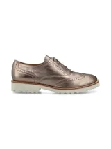 Zapato Oxford color bronce con detalles de perforaciones y suela blanca de goma.