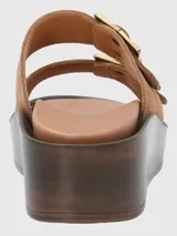 Sandalias de cuero color marrón con plataforma y dos tiras anchas con hebillas doradas.