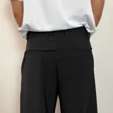 Pantalón sastrero color beige, de corte baggy, con pliegues en la cintura y bolsillos laterales.