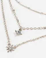 Collar corto de tres cadenas plateadas, una con bolitas, otra con strass y otra con dije de estrella de cinco puntas.