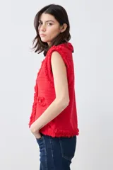 Chaleco tejido color rojo con cuello redondo, sin mangas, con desflecado en bordes y bolsillos frontales con botones dorados.