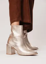 Bota de caña media color champagne de cuero, con horma redonda, taco cuadrado y pequeña plataforma. Cuenta con cierre del lado interno.