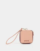 Monedero cuadrado de cuerina color rosa pálido con cierre perimetral y correa de mano. Tiene el texto "self lover club" bordado en el frente.