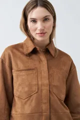 Chaqueta color tostado simil gamuza con cuello clásico, cierre con botones a presión, bolsillos de parche en el pecho y corte recto.