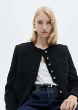 Chaqueta negra de tweed con cuello redondo, cierre frontal con botones plateados, mangas largas con puños abotonados, dos bolsillos de parche frontales y terminaciones deshilachadas.