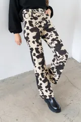 Pantalón de jean color crema con estampado de manchas de vaca en negro, corte recto y tiro alto.