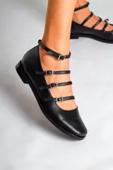 Chatas de cuero negro con punta fina, cuatro tiras horizontales con hebilla y pulsera al tobillo.