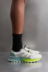 Zapatilla deportiva para carreras de montaña, color blanco con detalles en gris, verde y amarillo. Parte superior fabricada en tejido de punto transpirable con zona de puntera y talón recubiertas de material Shield Protect Max que protege de la abrasión. Ajuste de los cordones mediante pieza técnica. Tirador en la parte posterior para facilitar el calce. Plantilla interior OrthoLite® extraíble. Suela con tecnología Spume Foam que garantiza ligereza y confort.