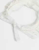 Vincha tipo bandana de tela blanca con bordado de flores y terminaciones con borlas. Se ata con lazos.