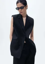 Americana sin mangas de lino color negro, con cuello de pico y solapas con muesca. Presenta dos bolsillos laterales de ribete y diseño oversize.