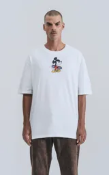 Remera blanca de algodón con cuello redondo y calce oversize. Estampado en la espalda de Mickey Mouse andando en skate con llamas y texto "Hot Diggity Skate Dogs".