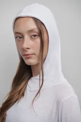 Camiseta blanca de manga larga confeccionada en tejido fino, suave y ligero. Presenta capucha amplia y silueta relajada.