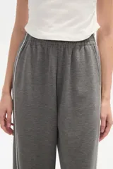 Pantalón deportivo negro de corte ancho y tiro alto, con cintura elástica y cordón ajustable. Presenta una raya blanca vertical a cada lado.