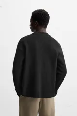 Cárdigan negro de punto con lana y algodón, corte regular, cuello solapa, manga larga y cierre frontal con botones.