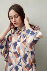 Camisa estampada con figuras geométricas en tonos azul, marrón y beige. Corte relajado, manga tres cuartos y botones al frente.