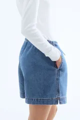 Short de denim azul claro, con cintura elástica y cordón ajustable. De corte holgado con bolsillos laterales y bajo recto con abertura lateral corta.