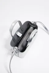 Bolso de mano plateado de piel con estructura rígida y tamaño mini. Tiene logo metálico, acabados metálicos plateados, cierre con cremallera e interior con logo grabado BIMBA Y LOLA.