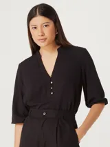 Blusa femenina de escote en V, con botones frontales y mangas tres cuartos.