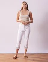 Pantalón capri blanco de algodón con bolsillos delanteros y traseros simulados, pretina elastizada con broche interno y cierre. Terminación de ruedo con aplique calado tipo crochet.