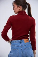 Polera de cuello alto color bordó, de tejido acanalado y manga larga.
