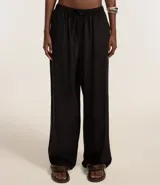 Pantalón femenino de corte fluido, color beige claro, con cintura elástica ajustable mediante un lazo.