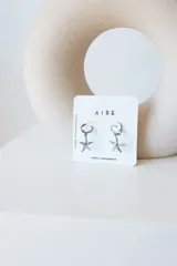 Par de aros dorados con forma de estrella de mar colgando de un aro pequeño.