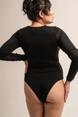 Body negro de lycra de manga larga con escote cruzado con tiras con brillos y broches en la entrepierna con fundillo de algodón.