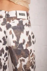 Pantalón wide leg blanco con estampado de vaca, con cierre y botón en la cintura.