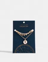 Collar corto dorado de tres capas: una con mostacillas doradas, otra con dijes de corazones y otra con dije circular rosa.