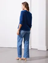 Blusa blanca de poliéster y elastano, con cuello a la base, escote en V y mangas tres cuartos. Presenta dos bolsillos frontales con cierre metálico dorado.