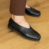 Zapato bajo de cuero negro con punta cuadrada y detalle de cierre en la capellada. Interior forrado en cuero color suela y suela de madera con inclinación de 0,5 cm.