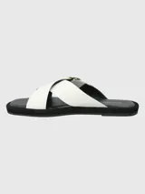 Sandalias de cuero sintético color blanco, con dos tiras anchas cruzadas sobre el empeine y hebilla circular dorada. Plataforma plana color negro.
