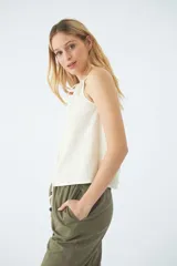 Blusa sin mangas color crudo, con cuello halter y cordón ajustable.