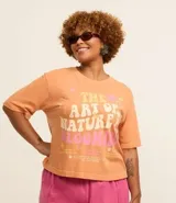 Remera color durazno de corte cuadrado con cuello redondo y mangas cortas. Estampa frontal con flores y la frase "The art of nature is blooming".