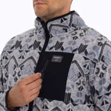 Campera polar para hombre con cierre frontal completo, cuello alto y un bolsillo con cierre en el pecho. Diseño con estampado geométrico en tonos marrones y verde oliva.