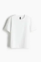 Remera blanca de algodón con cuello redondo y mangas cortas con detalle de puntilla.