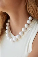 Collar de cuentas esféricas grandes de acrílico blanco, ensartadas en un cordón claro.