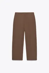 Pantalón marrón de tiro medio con trabillas en la cintura, bolsillos laterales, pinzas delanteras y bajo ajustable con trabilla y botón.