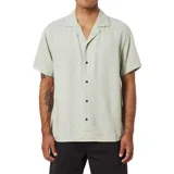 Camisa de manga corta color verde claro, con cuello tipo cubano y cierre frontal con botones marrones.