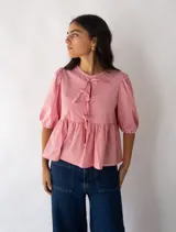 Top a rayas rojas y blancas con corte peplum y mangas abullonadas. Tiene lazo en el escote y es reversible.