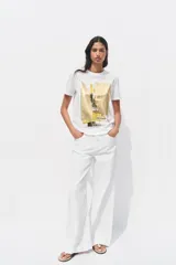 Camiseta blanca de manga corta y cuello redondo con estampado metalizado en el frente.