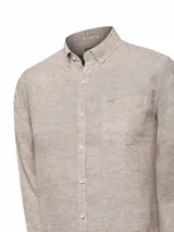 Camisa de manga larga color beige claro, confeccionada en lino orgánico. Tiene cuello abotonado, bolsillo en el pecho con logo bordado y detalles en contraste en el interior.