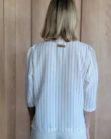 Camisa color beige claro con cuello con volados y mangas 3/4 abullonadas.