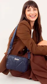 Bandolera pequeña de símil cuero color marrón, con diseño acolchado en forma de rombos. Posee doble cierre metálico en el compartimento principal, bolsillo trasero y correa ajustable de tela tipo galón.