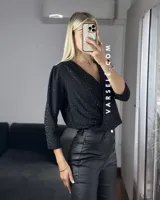 Blusa negra con estampado de lunares blancos, escote en V cruzado, mangas 3/4 abullonadas y hombreras. Talle único abarca hasta L.