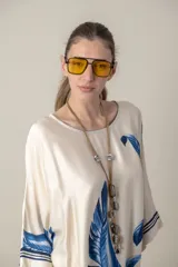 Vestido largo color natural con estampado de hojas de palmera en tonos verdes. Tiene corte amplio tipo túnica, cuello redondo, mangas tres cuartos, bolsillos laterales y ruedo con ribete.