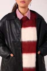 Trench negro de cuero ecológico con cuello clásico, cierre abotonado y bolsillos laterales.