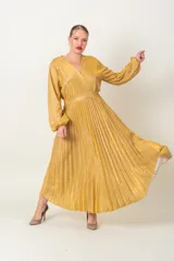 Vestido largo de lurex color dorado, con diseño cruzado y falda plisada de manga larga.